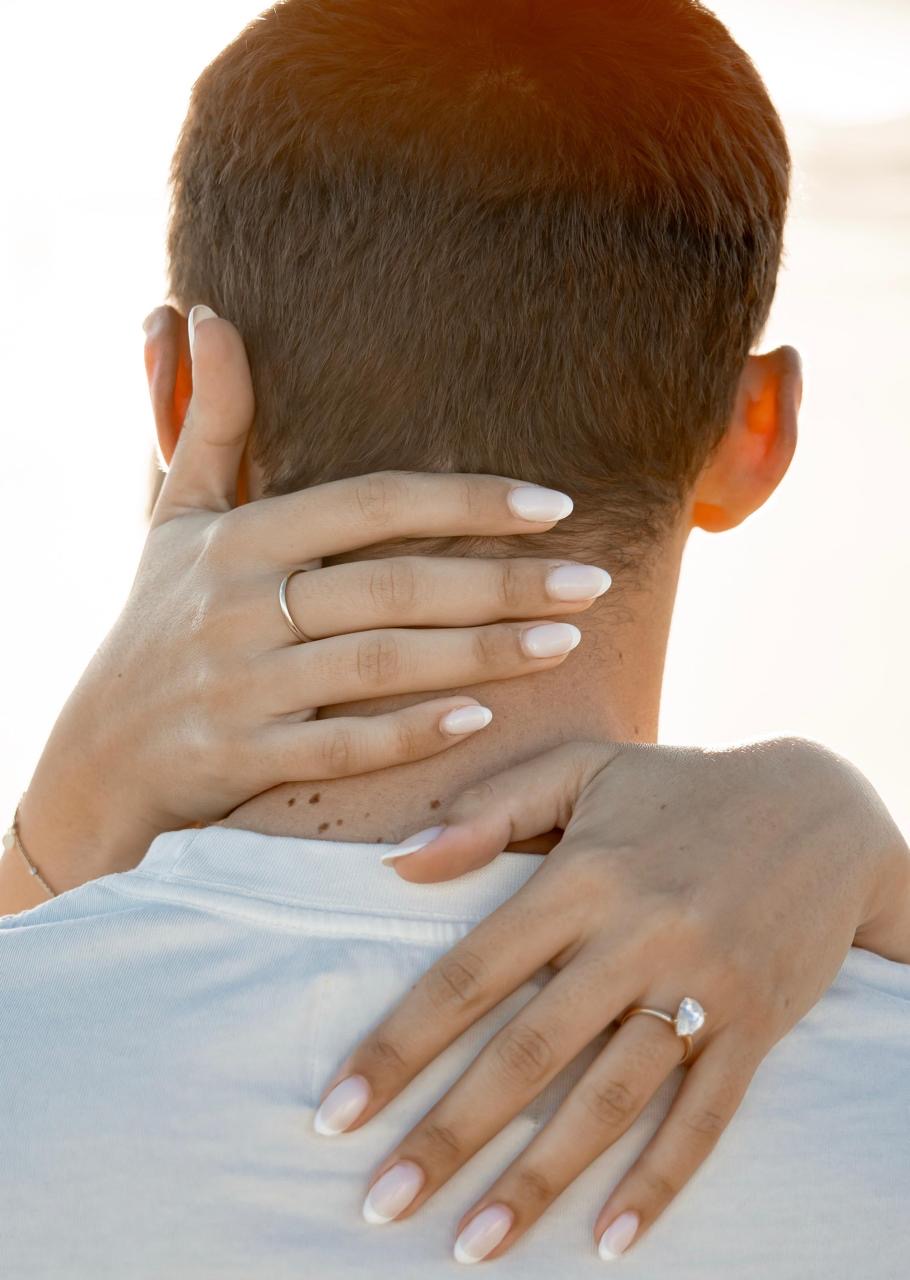 Haar hande om sy nek, met die ring sigbaar